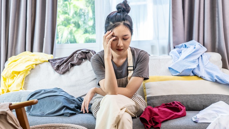 Woman sitting amidst pile of clothes