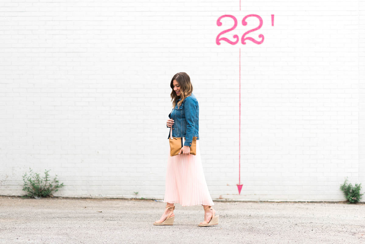 corals and cognacs wearing a pink maxi dress, madewell jean jacket and clare v striped clutch