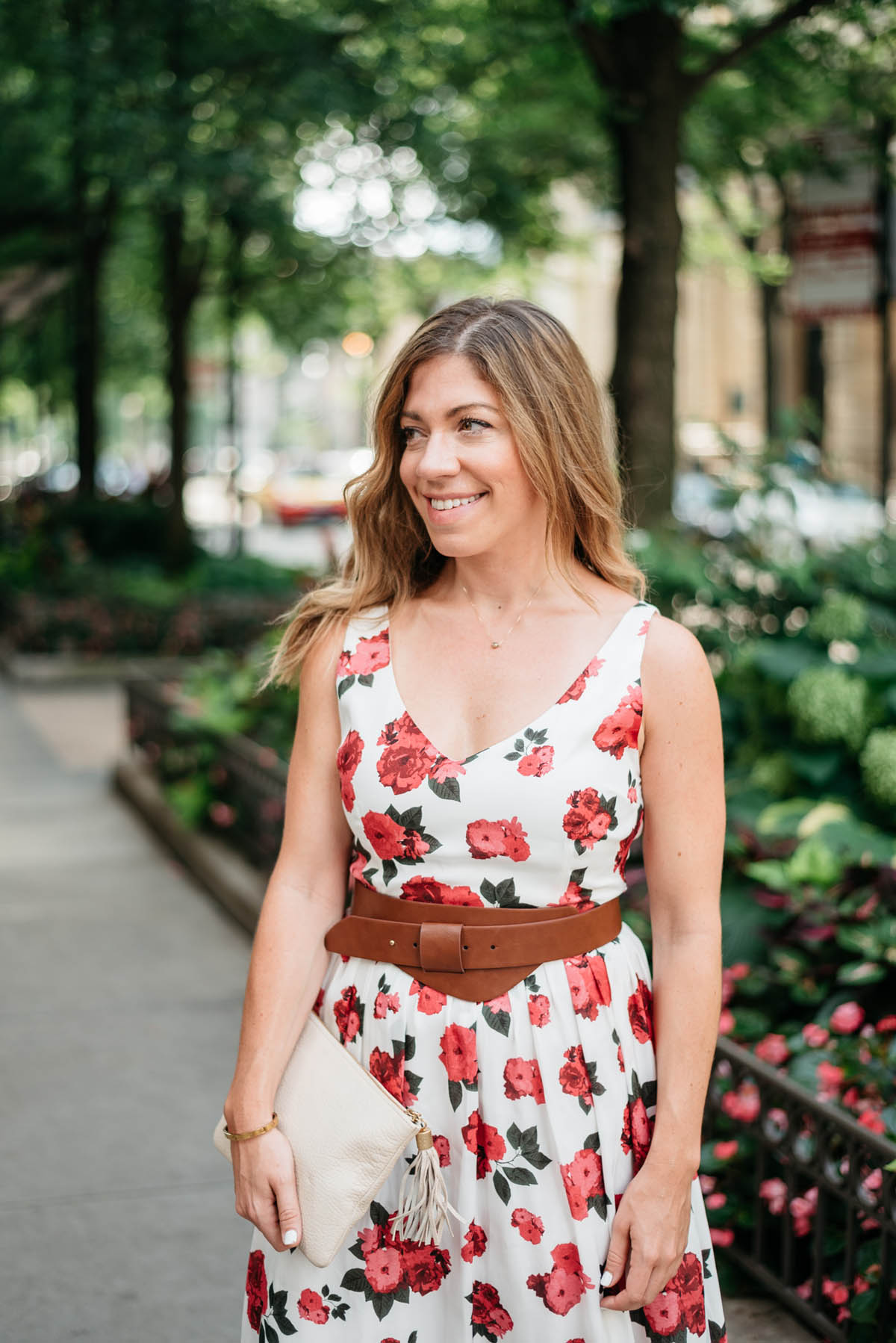 hallie wilson from corals and cognacs wearing a floral dress with a cognac belt around the waist